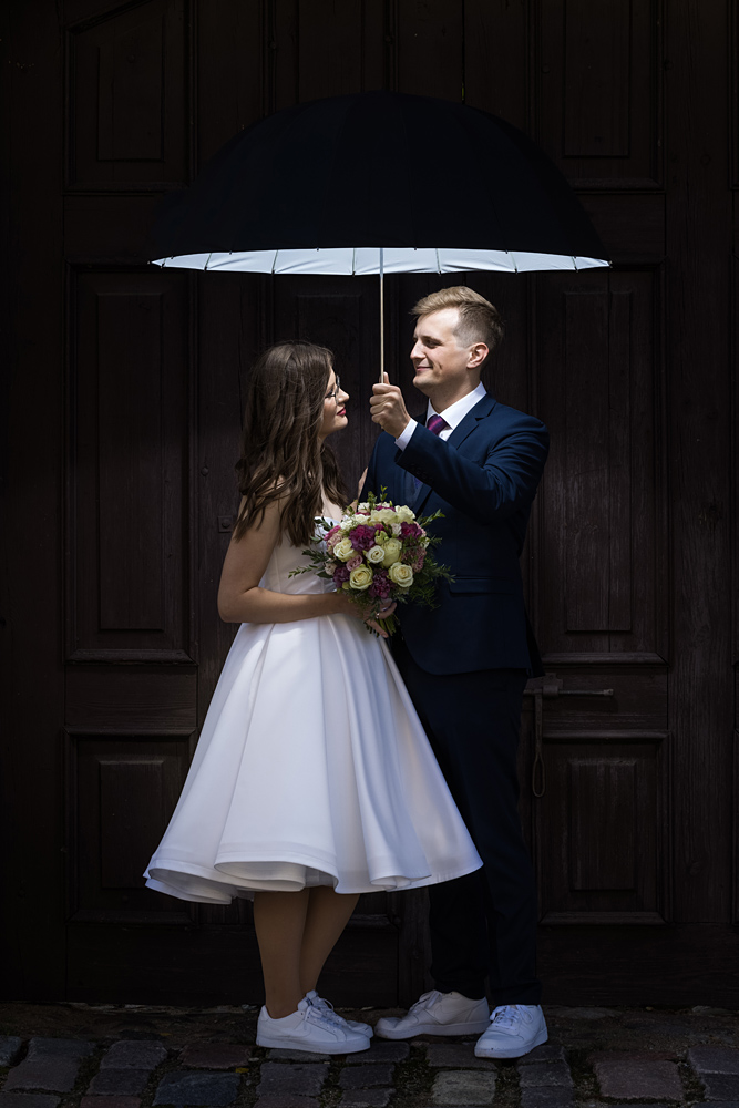 jaunieji po šviečiančiu skėčiu, dirbtinė šviesa, vestuvių nuotrauka